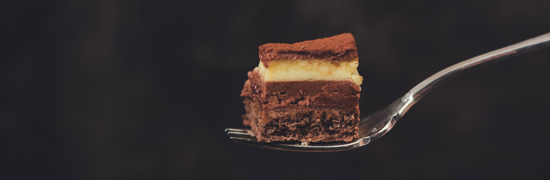 Image en gros plan d'une tranche de dessert au chocolat en couches sur une fourchette avec un fond sombre